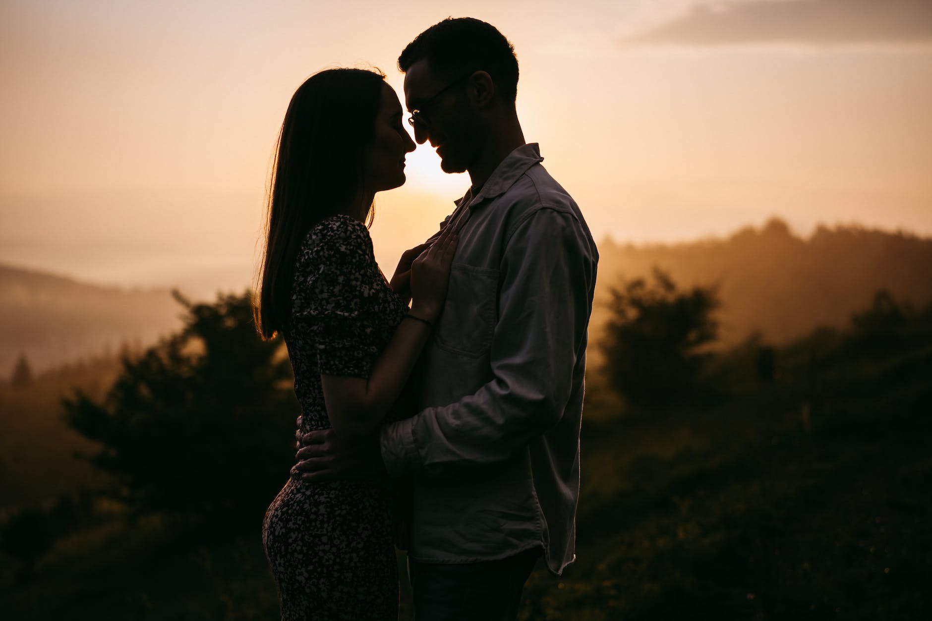 silhouettes of man and woman embracing at sunrise